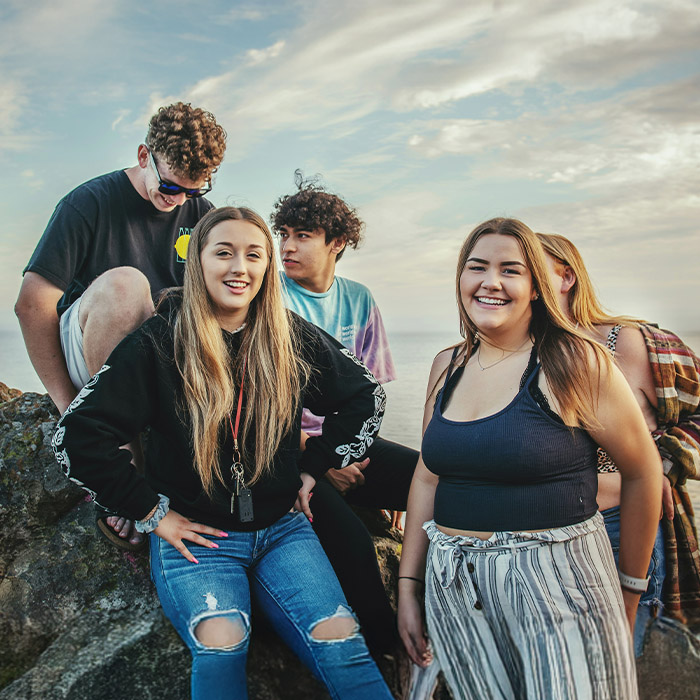 Some teenagers chilling by a rock by the sea